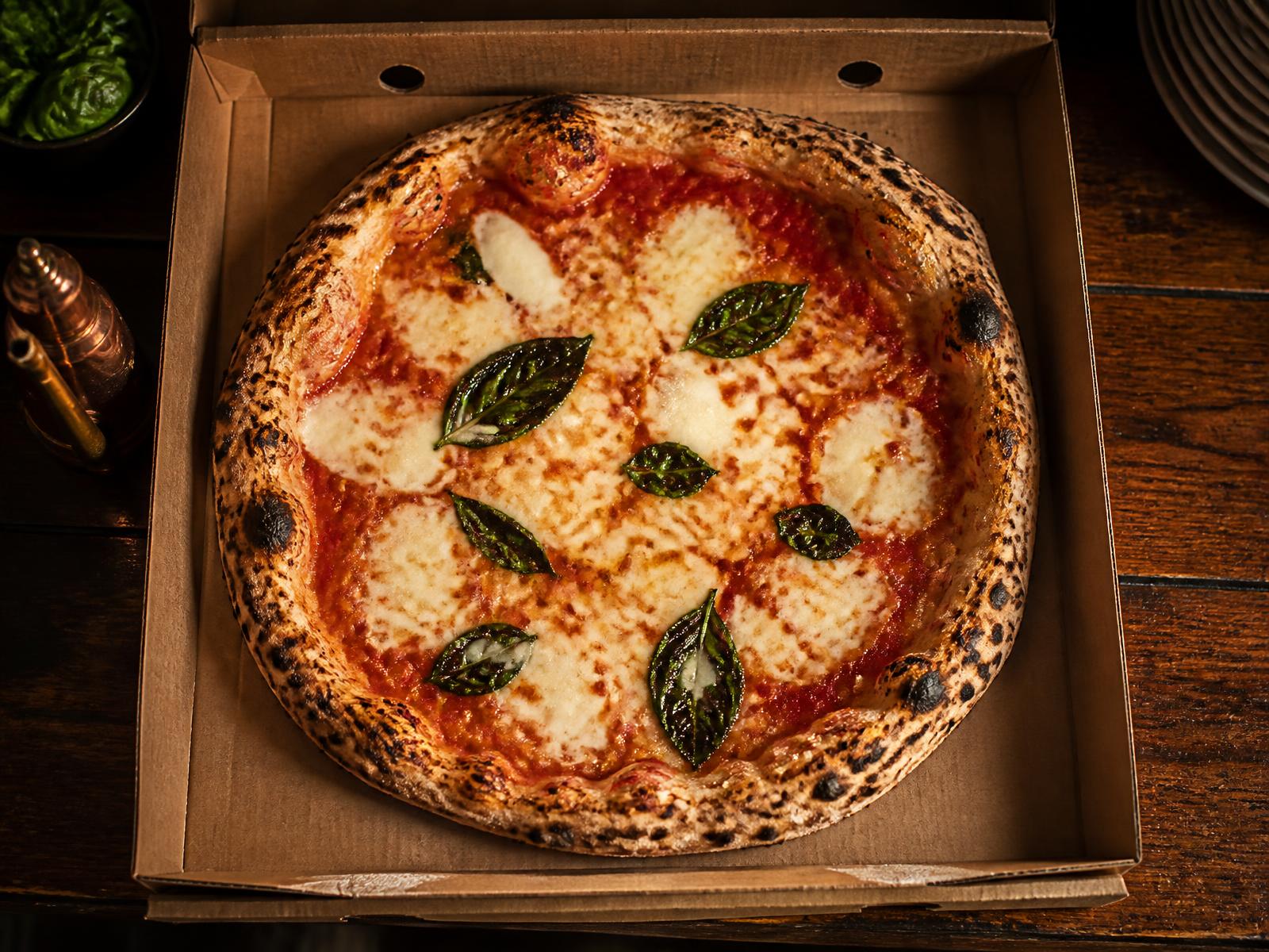 Pizza margherita appena sfornata nel cartone da asporto